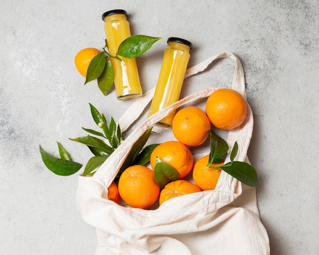Foto vista superior de laranjas em sacola com garrafas de suco
