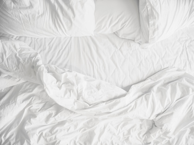 Vista superior de lençóis de cama desfeita e travesseiro