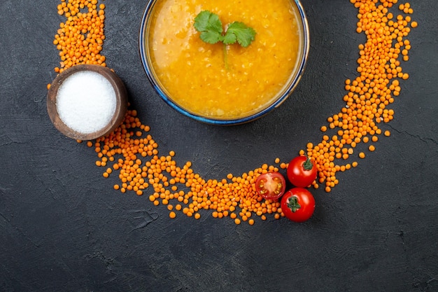 Vista superior de lentilhas vermelhas alinhadas em um círculo e deliciosa sopa de sal em fundo preto com espaço livre