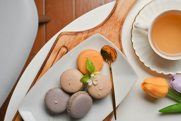 Vista superior de macarons franceses na bandeja de madeira e a xícara de chá na mesa de centro da sala de estar