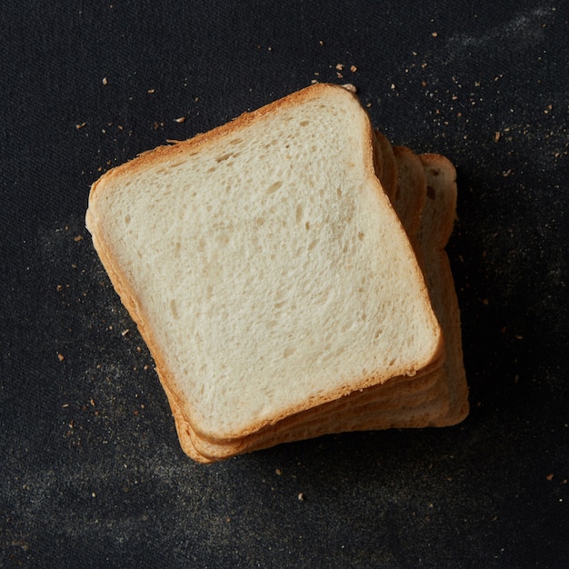 Vista superior de muitas fatias de pão branco, isoladas no fundo preto. Pão fatiado para fazer sanduíches no café da manhã, almoço, jantar, etc.