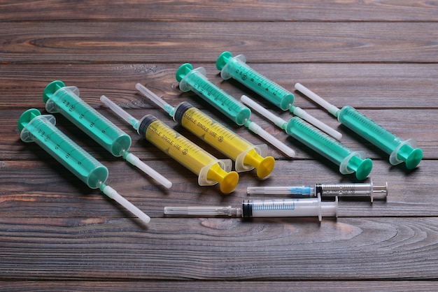 Vista superior de muitas seringas preparadas para injeção em fundo de madeira Conceito de tratamento com espaço de cópia