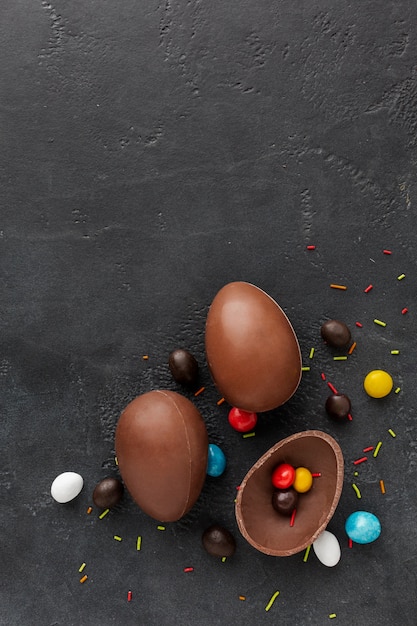 Vista superior de ovos de páscoa de chocolate com doces coloridos dentro e copie o espaço