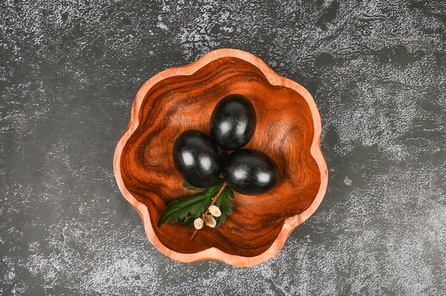 Vista superior de ovos escuros na placa de madeira. Conceito de Páscoa preto.