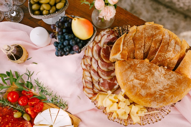 Vista superior de pão fresco macio com presunto com banha e queijo duro em um prato sobre um pano rosa esvoaçante