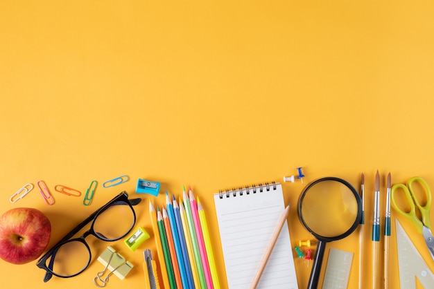 Foto vista superior de papelaria ou material escolar em fundo amarelo