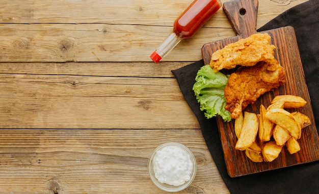 Foto vista superior de peixe e batatas fritas com garrafa de ketchup e espaço de cópia