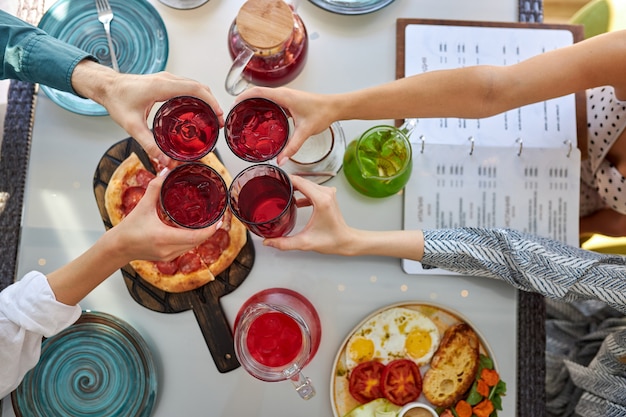 Vista superior de pessoas tilintando taças com vinho tinto