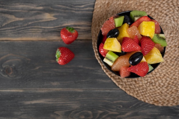 Vista superior de salada de frutas frescas em uma tigela no conceito de comida vegetariana de fundo de madeira