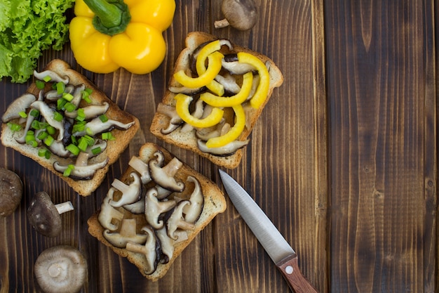 Vista superior de sanduíches com shiitake de cogumelos e vegetais na madeira marrom