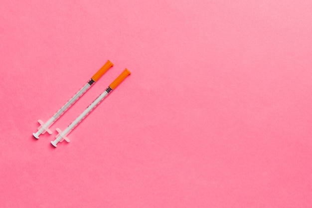 Vista superior de seringas de insulina prontas para injeção em superfície colorida