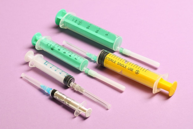 Vista superior de seringas médicas com agulhas em fundo roxo com espaço de cópia Conceito de tratamento de injeção