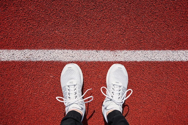 Vista superior de tênis de corrida masculino branco perto da linha de partida no estádio de fitness e estilo de vida saudável