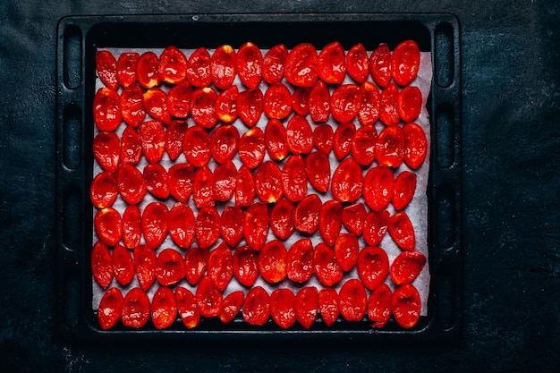 Foto vista superior de tomates secos ao sol cortados em fatias em uma bandeja em um fundo preto