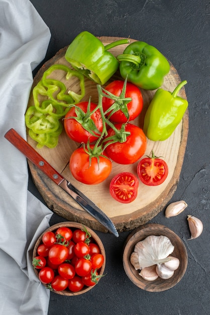 Vista superior de tomates vermelhos frescos com alho e pimentão verde na superfície escura