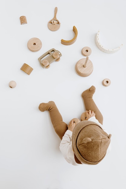 Vista superior de um bebê bonito de um ano brincando com brinquedos Conceito de moda de bebê Cores neutras