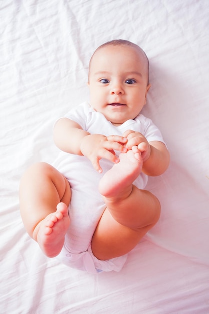 Vista superior de um bebê fofo deitado em uma cama com os pés levantados