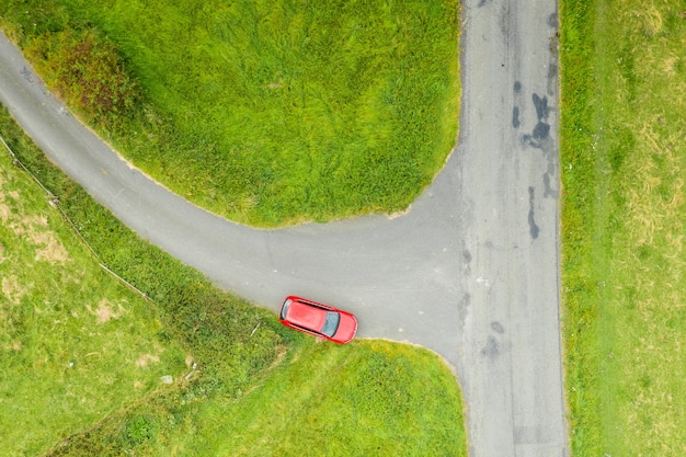 Vista superior de um carro vermelho parado em uma encruzilhada em um campo