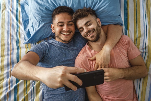 Vista superior de um casal gay deitado e fazendo selfie