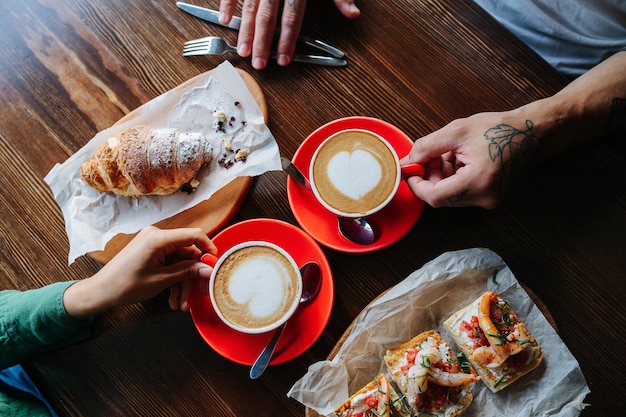 Vista superior de um casal sentado em um café em frente um do outro tomando café