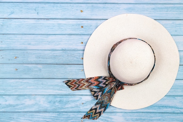 Vista superior de um chapéu de palha branco sobre um fundo azul de madeira. O conceito de férias de verão.
