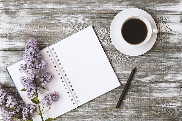 Vista superior de um diário ou caderno, lápis e café e uma flor roxa em uma mesa de madeira cinza. projeto liso.