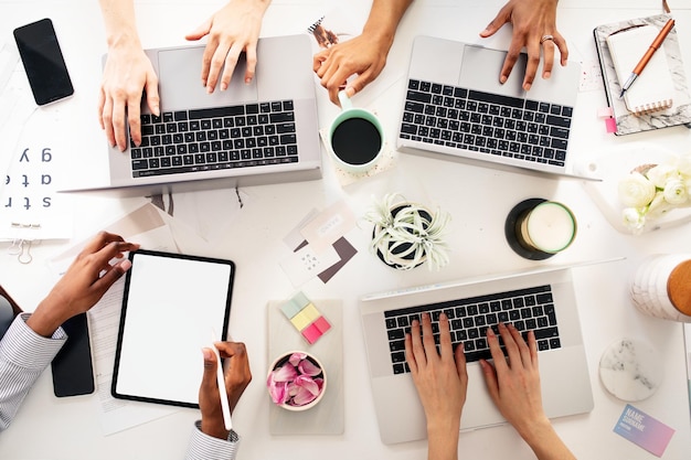 Vista superior de um grupo diversificado de mãos trabalhando em colaboração em laptops e um tablet Vista superior do trabalho em equipe 39s mãos trabalhando juntos com laptop e tablet Vista superior da equipe de negócios trabalhando juntos