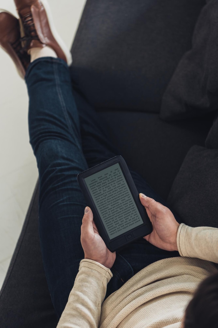 Foto vista superior de um homem estudando com ebook enquanto estava sentado no sofá com as pernas cruzadas