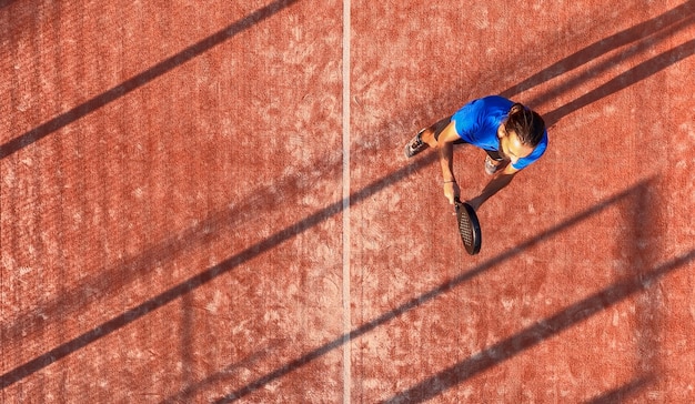 Vista superior de um jogador de padel que está em sua posição esperando para acertar a bola. Quadra ao ar livre.