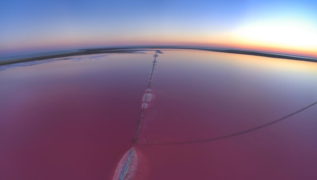 Vista superior de um lago rosa salgado brilhante e um caminho ao longo dele