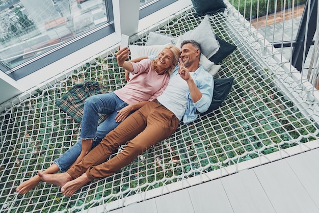 Vista superior de um lindo casal maduro fazendo selfie pelo telefone inteligente e sorrindo