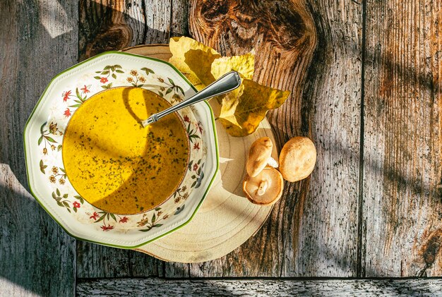 Vista superior de um prato com sopa de abóbora e cogumelos cores quentes de fundo de madeira