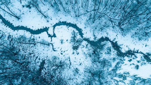 Vista superior de um riacho estreito e sinuoso em um inverno nevado