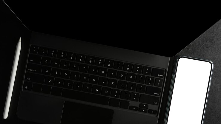 Foto vista superior de um tablet preto moderno ou computador touchpad com tela em branco do smartphone em uma mesa