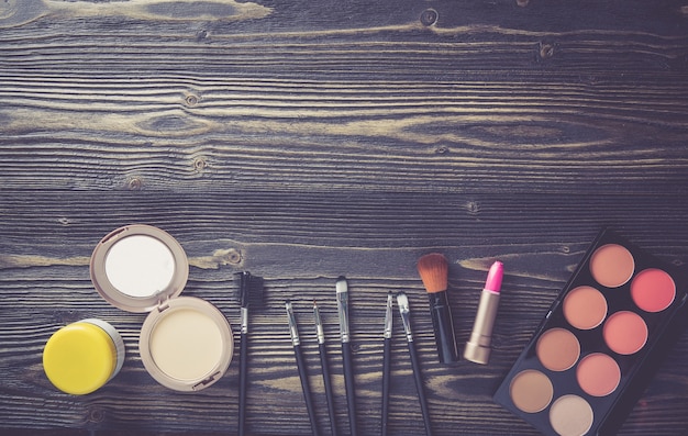 Vista superior de uma coleção de maquiagem cosmética no fundo da mesa de madeira.