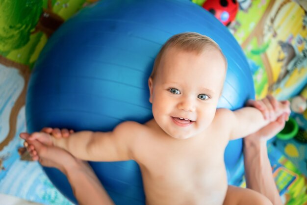 Vista superior de uma criança caucasiana fazendo exercícios na grande bola azul de fitness