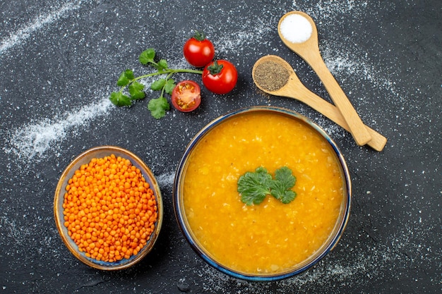 Vista superior de uma deliciosa sopa de lentilhas vermelhas em uma tigela servida com tomates verdes em fundo branco preto com espaço livre