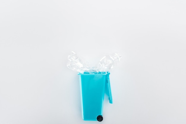 Vista superior de uma lixeira de brinquedo azul e uma garrafa de plástico vazia