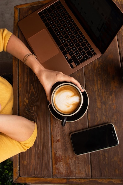 Vista superior de uma mulher em uma mesa de café com um computador e um smartphone