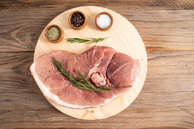 Vista superior de uma placa de madeira redonda com um grande pedaço de carne fresca de fazenda na mesa da aldeia o conceito de produtos naturais