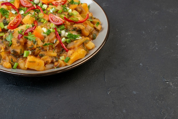 Vista superior de uma refeição saborosa com batatas e vegetais verdes no lado direito em fundo preto com espaço livre