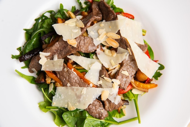 Vista superior de uma salada quente com parmesão de bife de rúcula e fatias de nozes