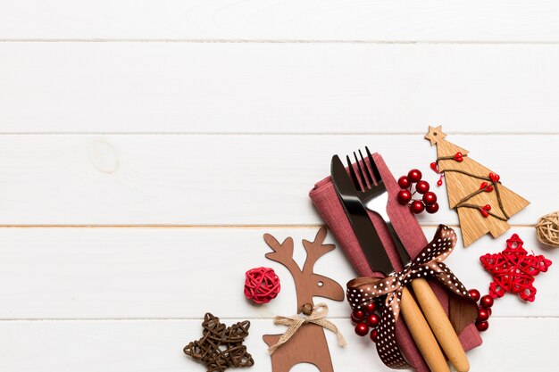 Foto vista superior de utensílios de ano novo em guardanapo com decorações do feriado e renas em fundo de madeira. jantar de natal com copyspace