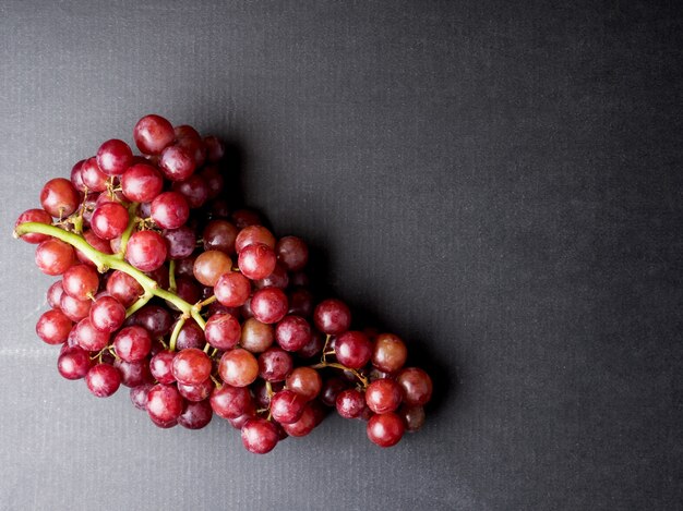 Vista superior de uvas vermelhas em um fundo preto. Espaço livre para o texto