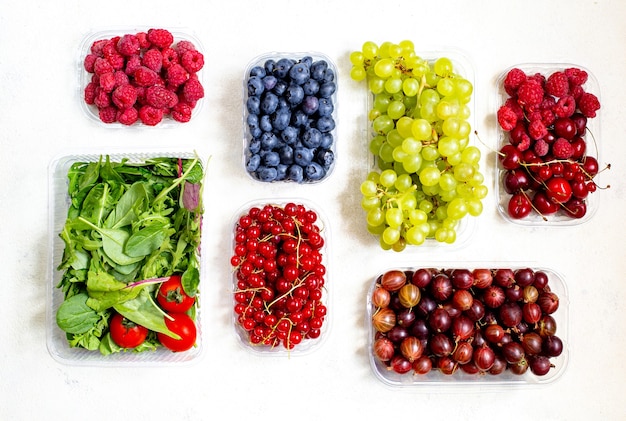 Vista superior de vegetais, frutas e bagas em caixas de plástico em fundo branco