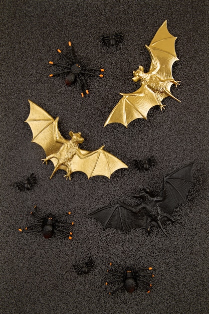 Vista superior de la decoración de Halloween con murciélagos de plástico negro y dorado sobre brillo