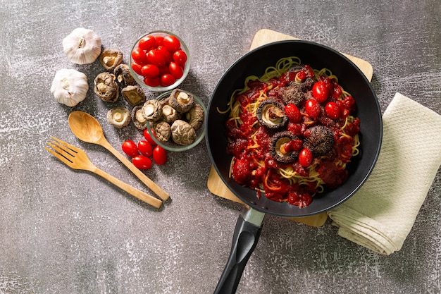 Vista superior de la deliciosa pasta a la boloñesa en una sartén cerca de los ingredientes