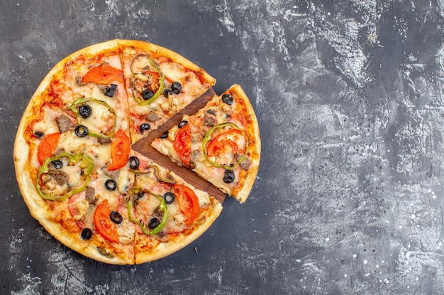 Vista superior de la deliciosa pizza de queso en rodajas y servida en una superficie gris