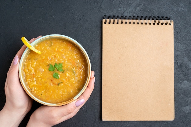 Vista superior deliciosa sopa de lentejas con placa de sujeción femenina en la superficie oscura