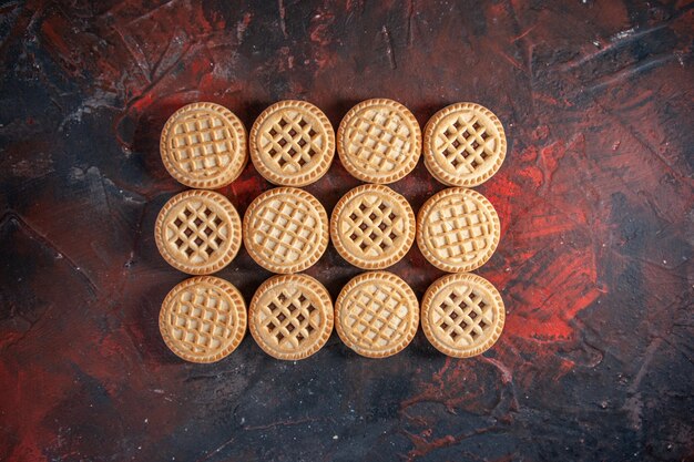 Vista superior de deliciosas galletas de azúcar dispuestas en filas sobre fondo de colores mezclados con espacio libre